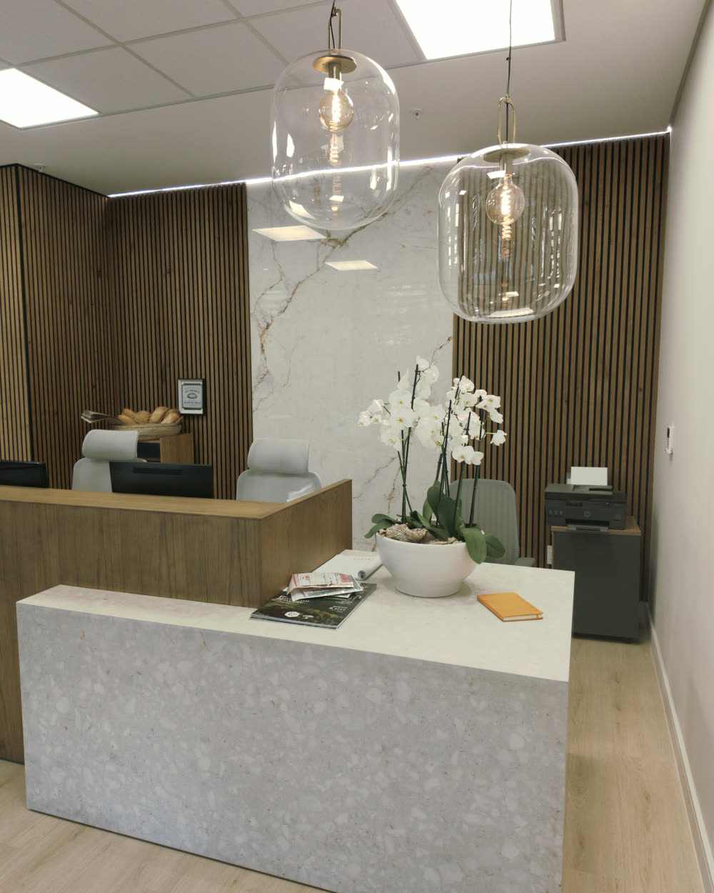 Reception at Dr Brink & Associates, Steyn City — terrazzo counter, timber slat walls and a white orchid