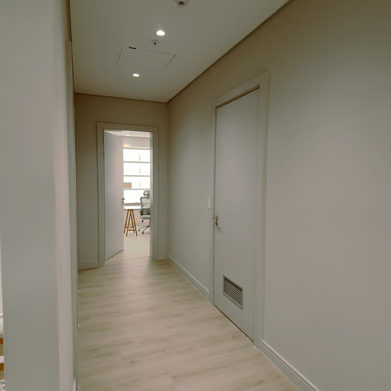 Bright corridor with pale oak flooring leading to an open consulting room doorway